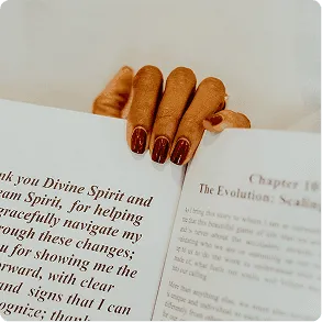 Freshly manicured nails resting on the pages of an open book about mindful living